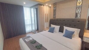 A modern hotel room with a large bed, a bedside table, and a window with curtains. - 1Br Near Mall At Grand Sungkono Lagoon Apartment (Surabaya)