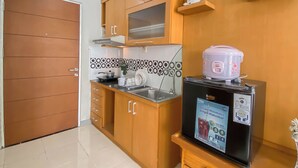 A compact kitchen with wooden cabinets, a built-in microwave, and a small sink. - Nice & Cozy Studio Apartment At Taman Melati Margonda (Depok)