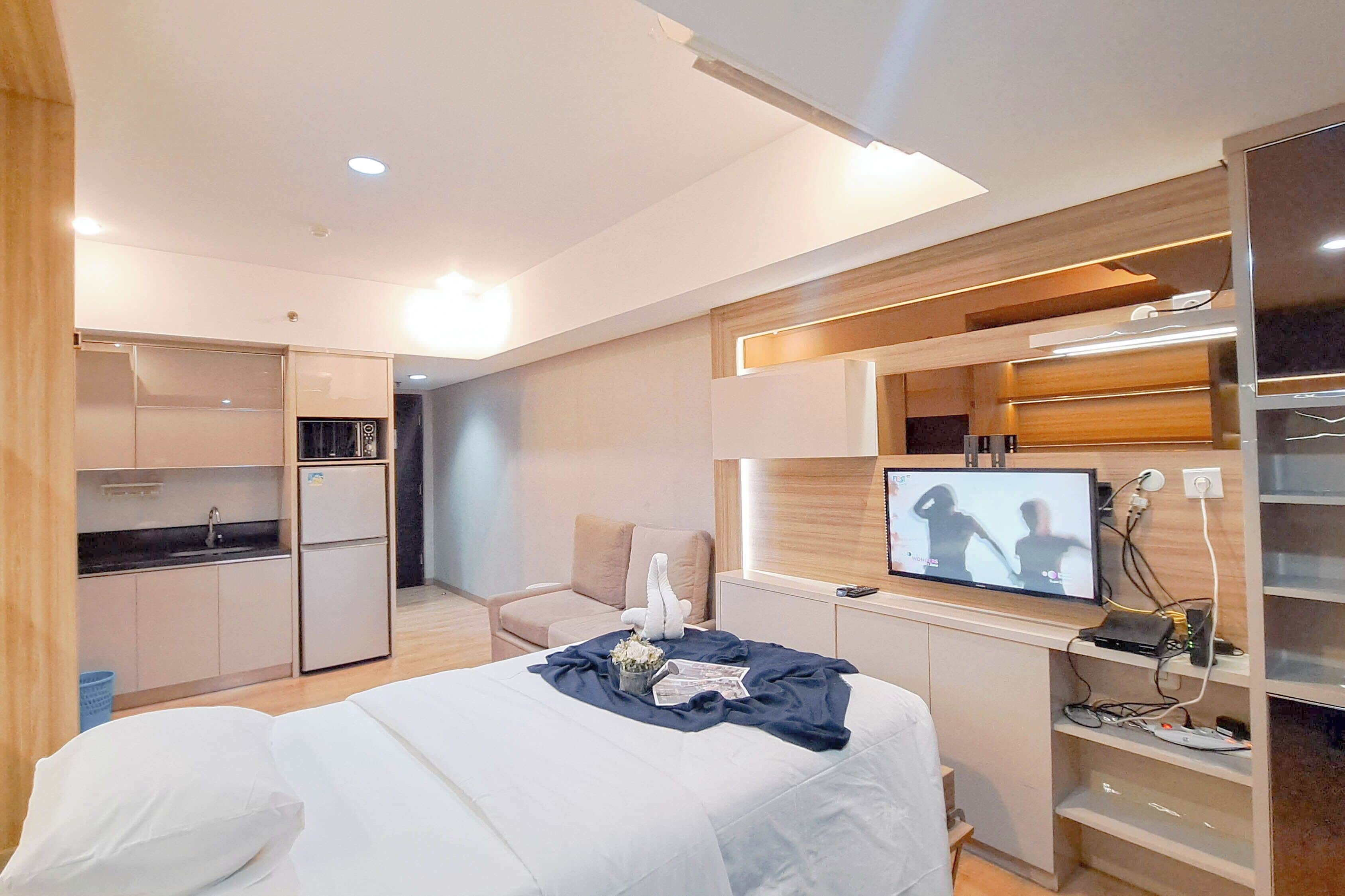 Une chambre d’hôtel moderne équipée d’un lit, d’une télévision, d’une kitchenette et d’un coin salon.