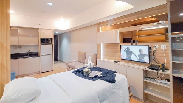 Ein modernes Hotelzimmer mit Bett, Fernseher, Küchenzeile und Sitzecke.