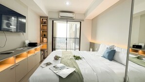 Une chambre d’hôtel moderne équipée d’un lit, de tables de chevet, d’une télévision et d’un balcon avec vue.