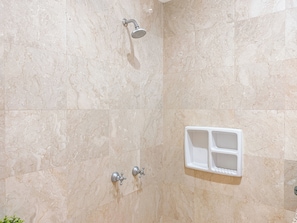 A bathroom with beige marble walls, a showerhead, and a white soap dish. - Spacious 2Br With Mall Access At Bellezza Apartment (Jakarta)