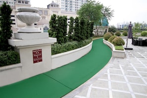 A curved green pathway with directional signage for a jogging track, playground, and tennis court. - Spacious 2Br With Mall Access At Bellezza Apartment (Jakarta)