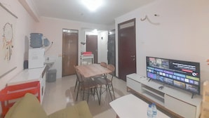 A compact living space with a dining area, a TV, and a kitchenette. - Basic 2Br At Gateway Pasteur Apartment (Cimahi)