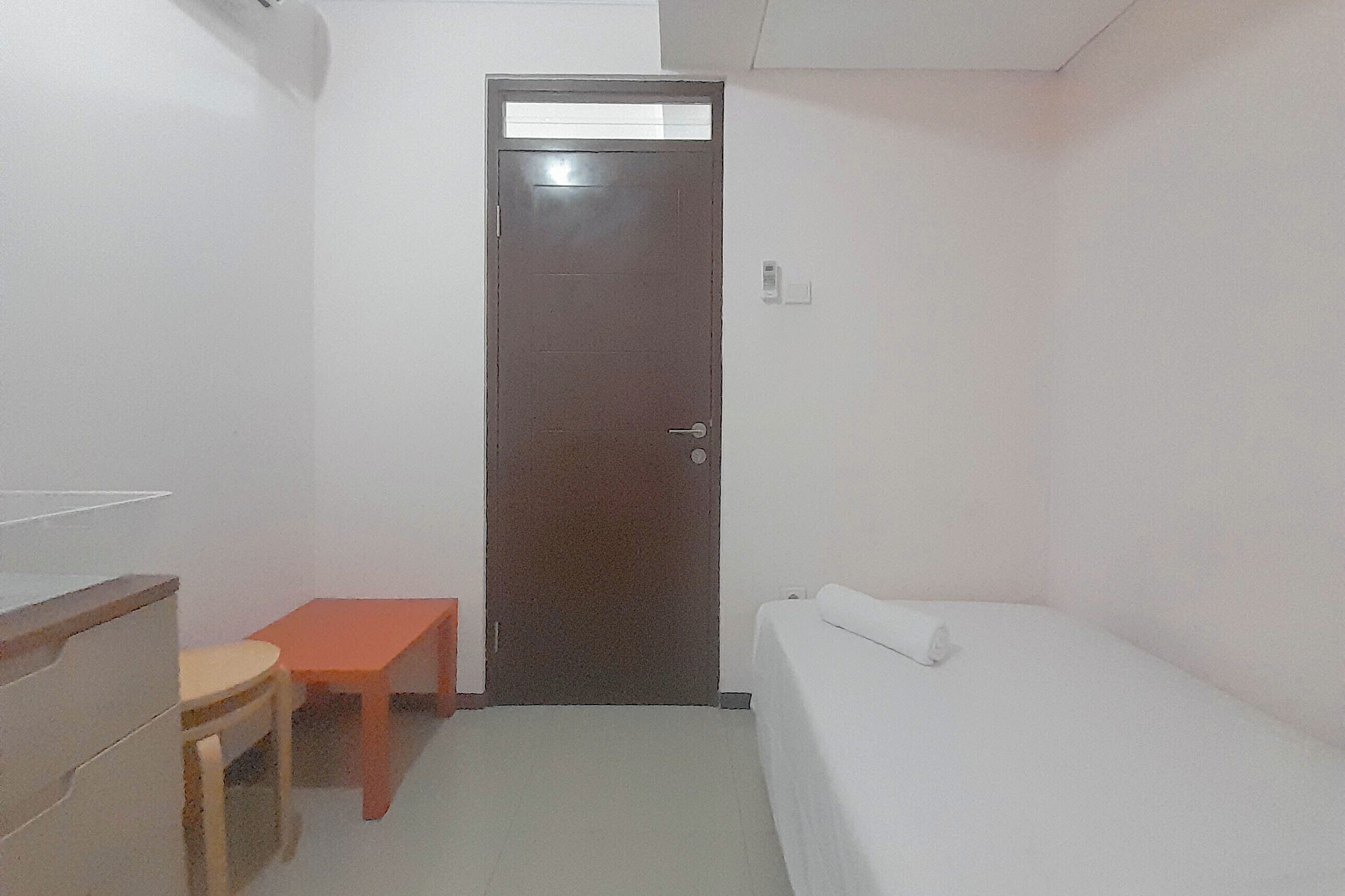 A small, single-room accommodation with a bed, a desk, and a chair.