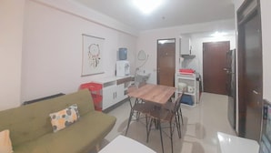 A compact living space with a dining table, a sofa, a water dispenser, and a refrigerator. - Basic 2Br At Gateway Pasteur Apartment (Cimahi)
