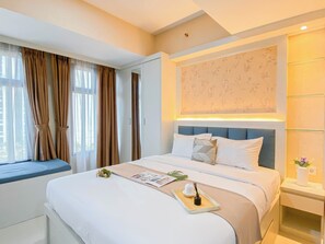 Ein Hotelzimmer mit einem großen Bett, einem Nachttisch, einem Fenster mit Vorhängen und einer Wand mit Blumenmuster.
