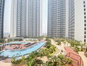 Ein Hochhaus mit Wohnungen, einem Schwimmbad und einem angelegten Garten.