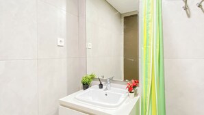 A bathroom with a white sink, a mirror, and a shower curtain. - Cream Toned And Compact Studio Apartment Pollux Chadstone (Cikarang)