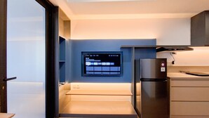 A modern kitchen with a built-in TV displaying a streaming service interface, a refrigerator, and a wooden countertop. - 1Br Near Alam Sutera Mall At Collins Boulevard Apartment (Tangerang)