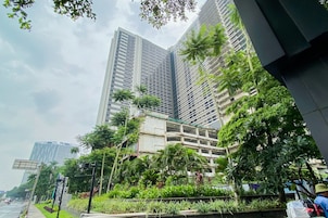 Un edificio moderno de gran altura con fachadas de vidrio y concreto, rodeado de exuberante vegetación y palmeras.