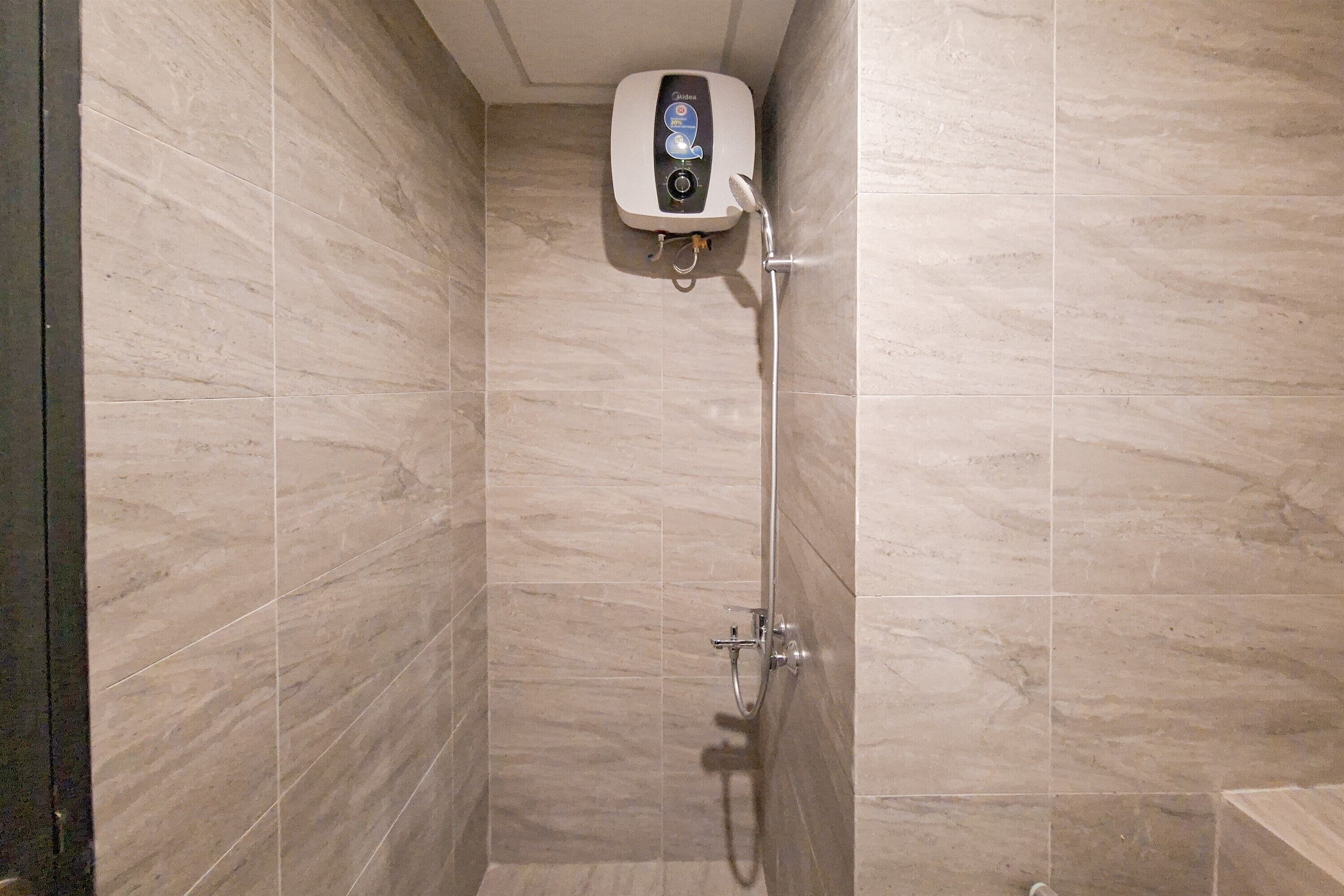 A bathroom with a built-in water heater, a showerhead, and a handheld shower attachment.