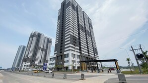 A modern high-rise building with a prominent corner entrance and a covered pedestrian area. - Warm Neutral 2Br At Meikarta Apartment (Cikarang)