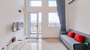 A modern living room with a sofa, TV, and a small table. - Studio Loft Apartment Near Living World Alam Sutera At Kingland Avenue (South Tangerang)