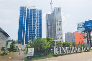 A sign for KINGLAND AVENUE with a modern building in the background. - Studio Loft Apartment Near Living World Alam Sutera At Kingland Avenue (South Tangerang)