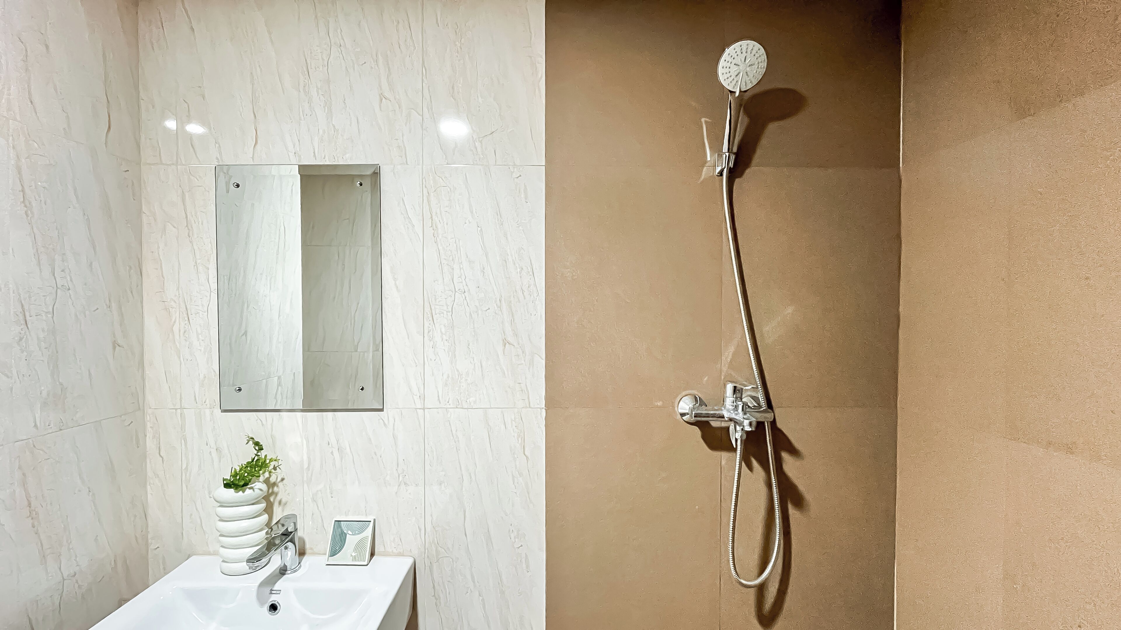 Ein Badezimmer mit einem weißen Waschbecken, einem Spiegel und einer Dusche inklusive Duschbrause.