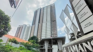 A high-rise building with multiple balconies and a sign indicating available space. - Good Deal Studio At Apartment Tamansari Bintaro Mansion (South Tangerang)