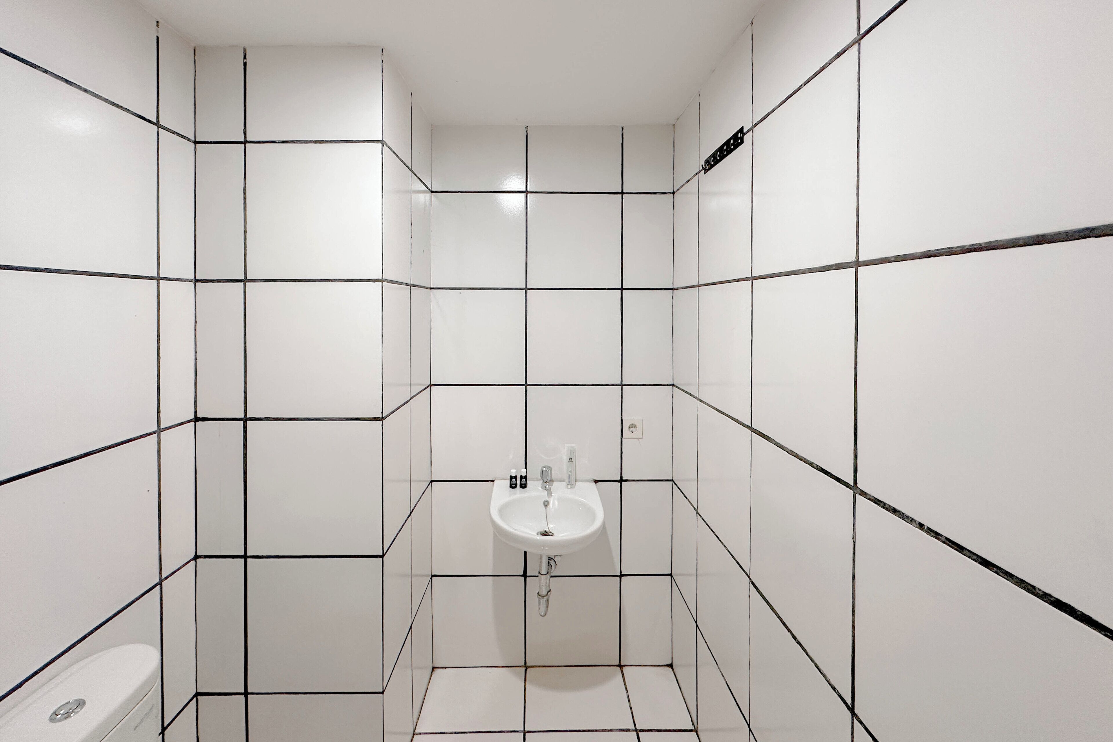 Egy kis, csempézett fürdőszoba mosdókagylóval és WC-vel.