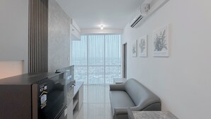 Un soggiorno moderno con un divano grigio, una TV a schermo piatto e un angolo cottura integrato.