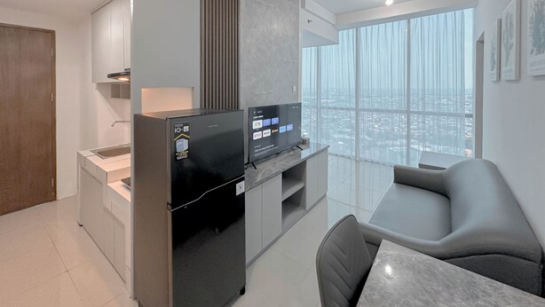 Una cucina moderna con frigorifero integrato, zona pranzo con divano grigio e ampia finestra vista città.