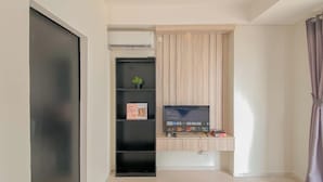 A modern room with a built-in TV, a small plant, and a shelf with a book. - Basic Studio At Daan Mogot City Apartment (Jakarta)