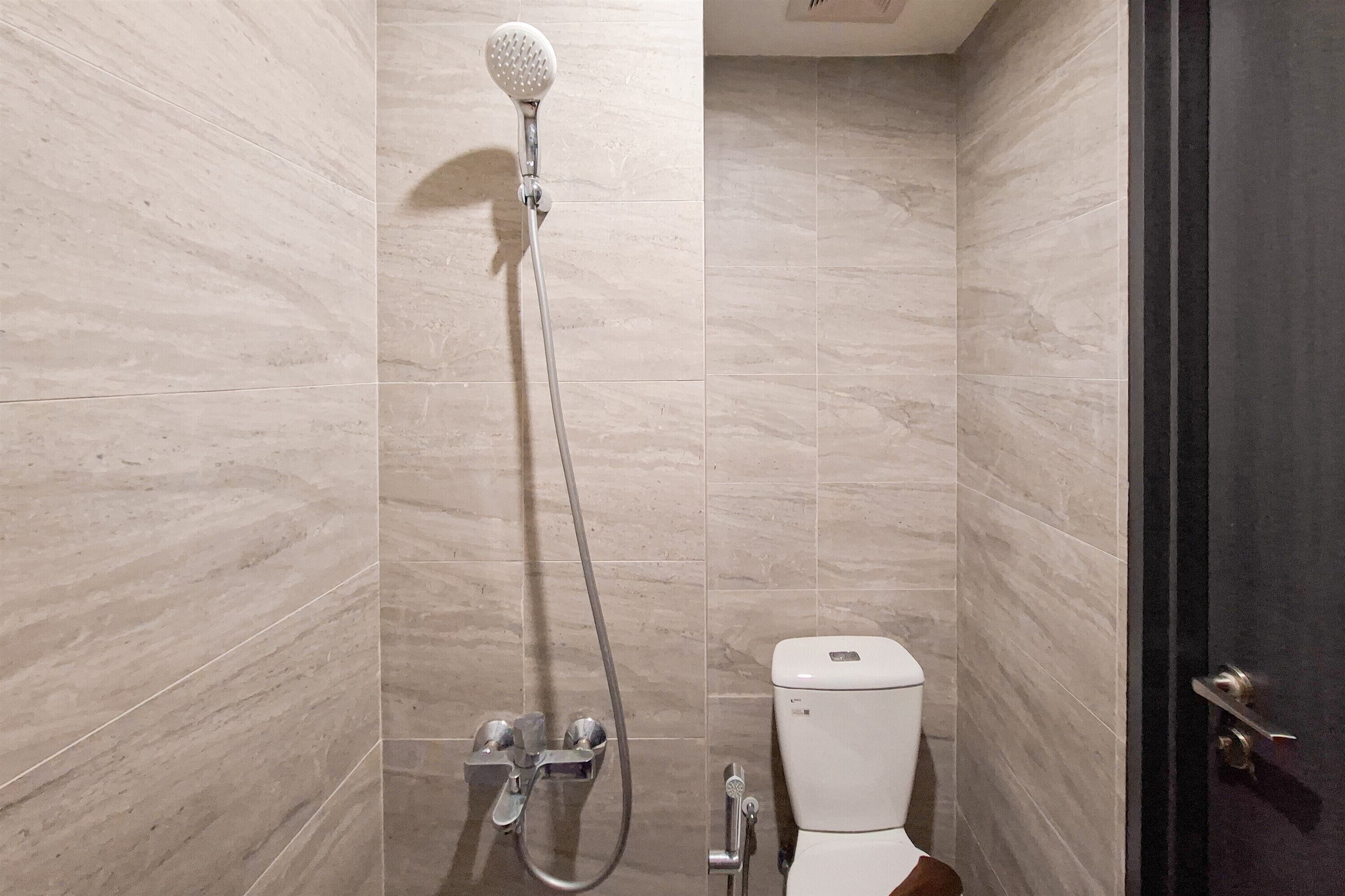 A bathroom with a shower, toilet, and a door.