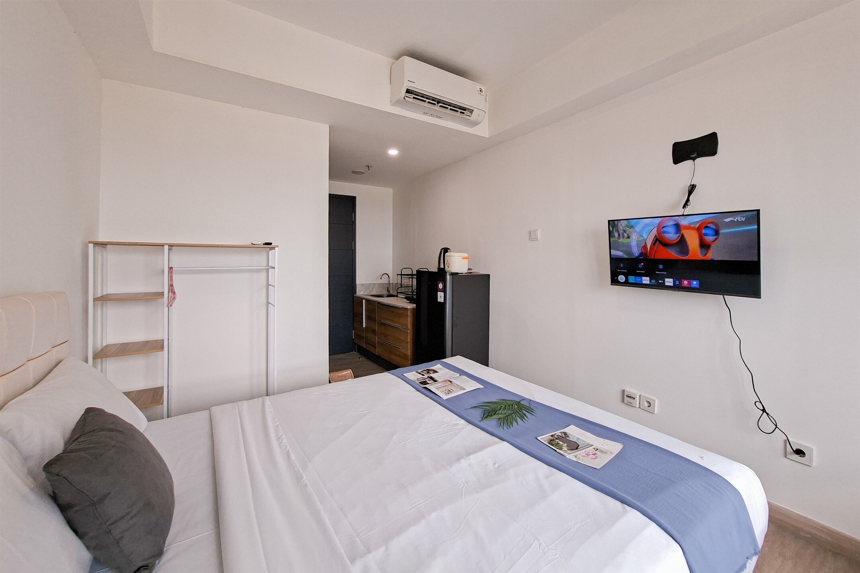 Camera d'albergo con un letto, una televisione a muro, una scrivania con una sedia e un armadio.