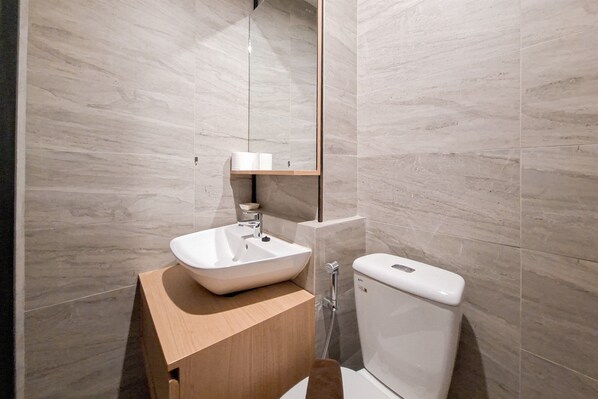 Une salle de bain moderne avec un lavabo blanc, un meuble-lavabo en bois et des toilettes.