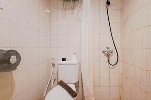 A small, tiled bathroom with a toilet, a shower, and a towel holder. - Homey And Restful 2Br At Mekarwangi Square Cibaduyut Apartment (Bandung)