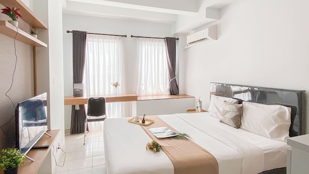 A modern hotel room with a bed, bedside table, and a desk with a chair. - Basic Look Studio Near Bekasi Station At Patraland Urbano Apartment (Bekasi)