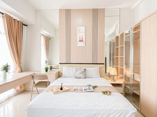 A modern hotel room with a bed, bedside table, lamp, and a wardrobe.