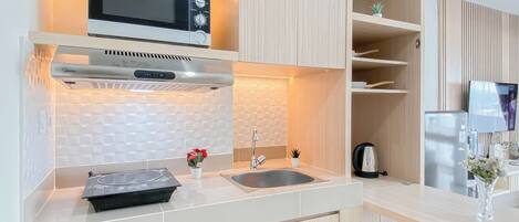 A modern kitchen with a microwave, stove, and sink. There are wooden cabinets and a countertop.