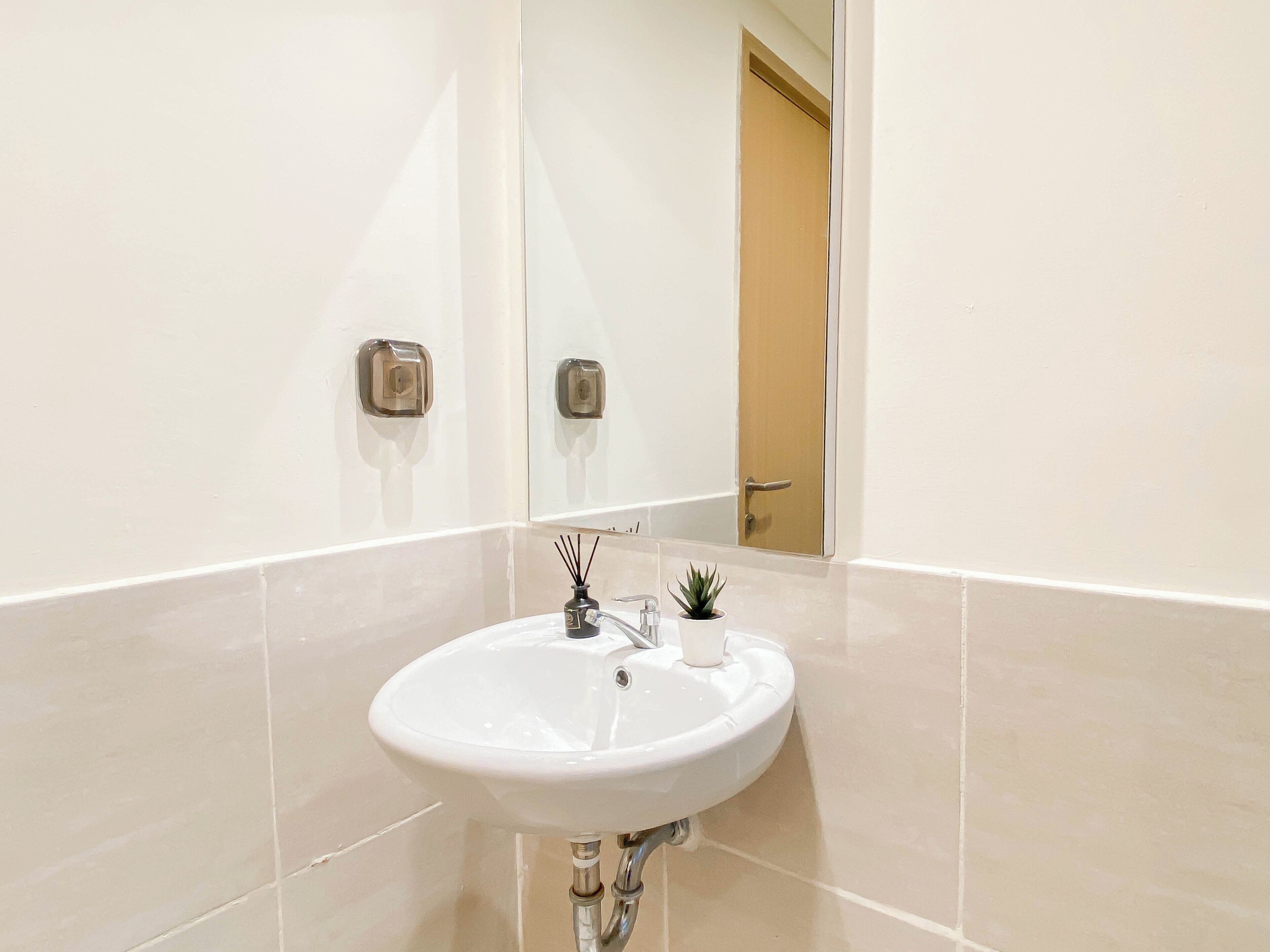 Un baño con un lavamanos blanco, un espejo y una puerta al fondo.