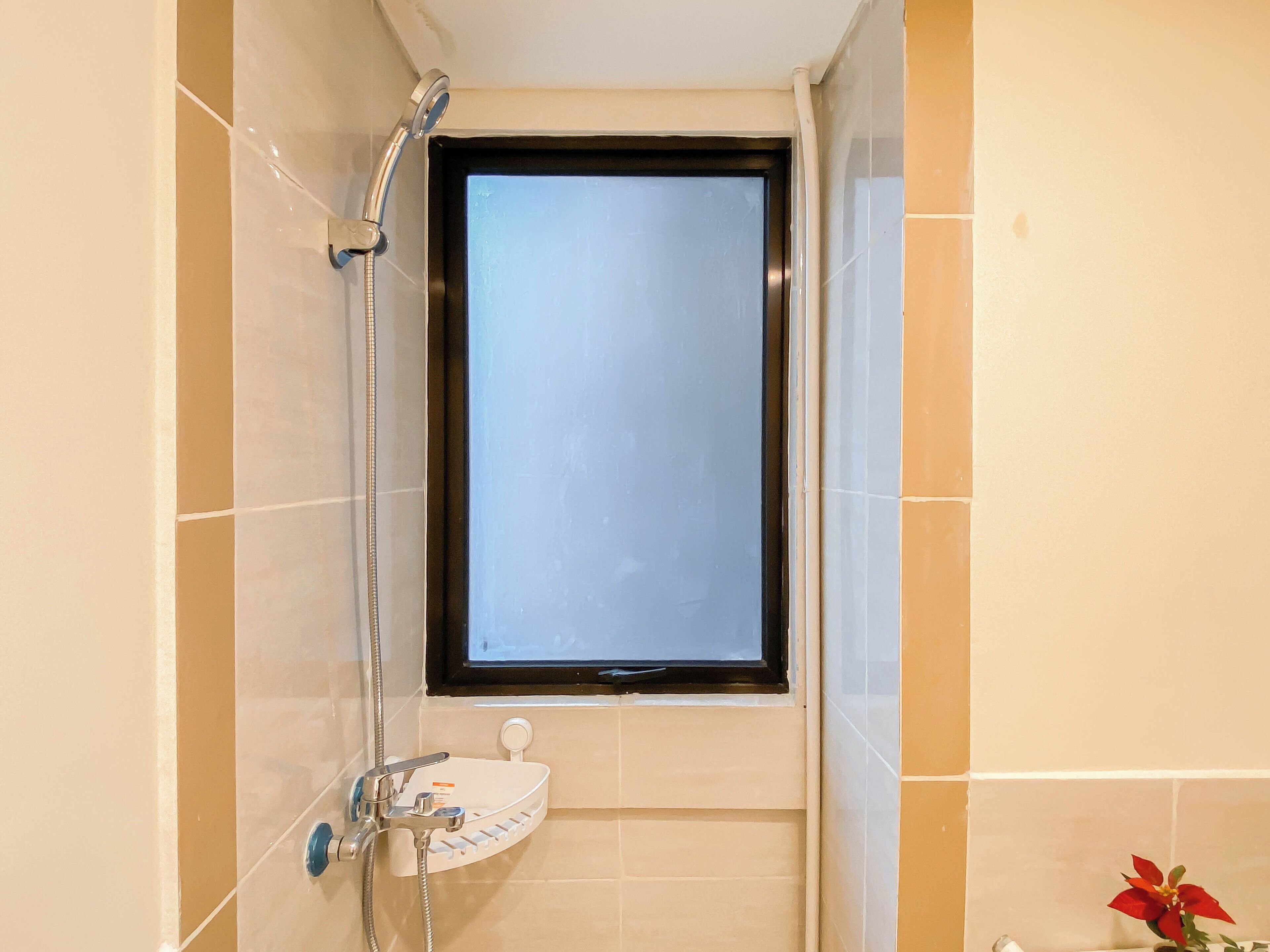Un bagno con doccia, lavandino e finestra.