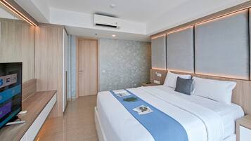 A modern hotel room with a large bed, a flat-screen TV, and a built-in air conditioning unit.