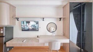 Una cocina moderna con refrigerador empotrado, televisor de pantalla plana montado en la pared, espejo redondo sobre la encimera y cabina de ducha con mampara de vidrio.