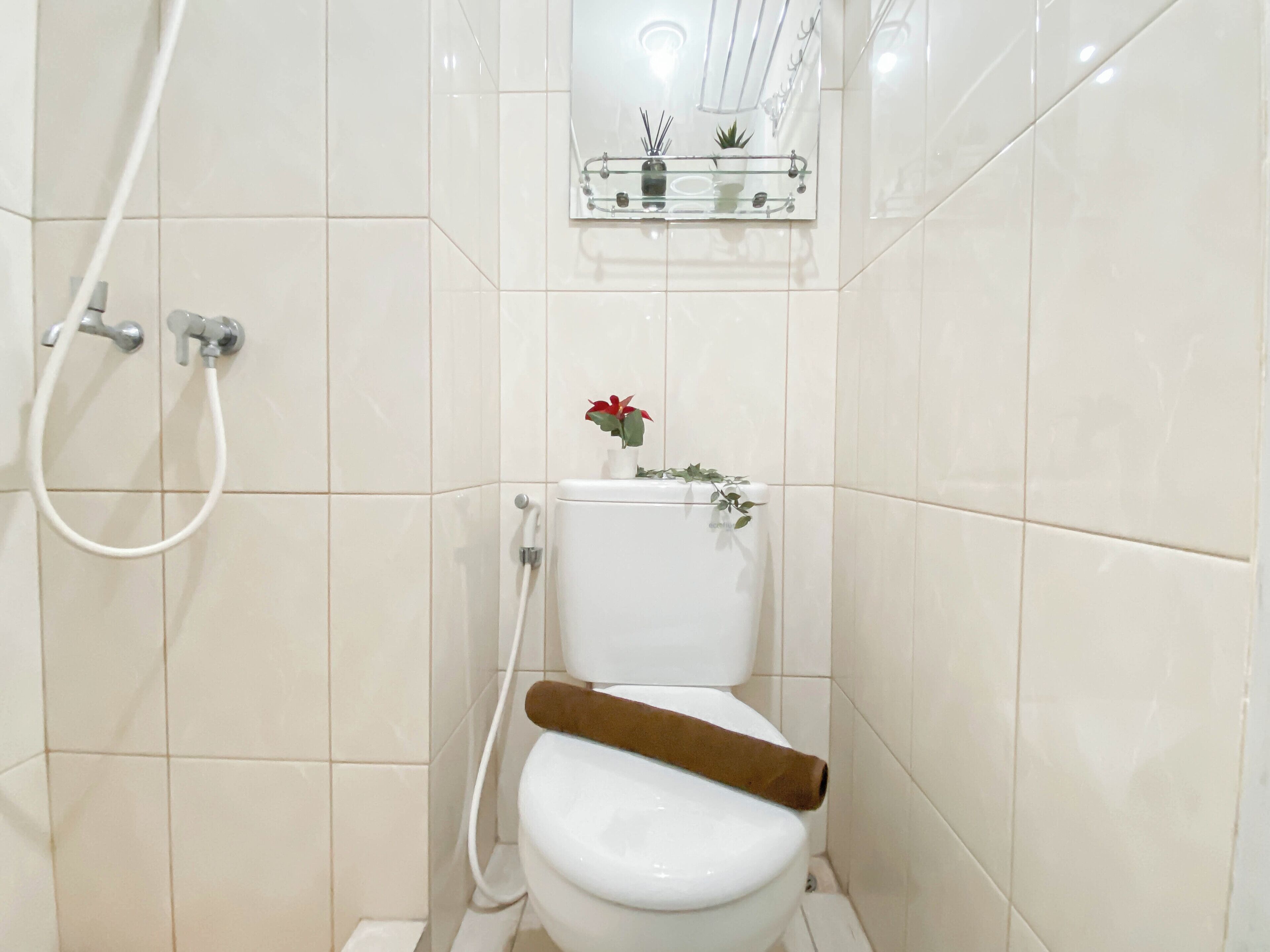 Ein Badezimmer mit Toilette, Dusche und Ablage für Toilettenartikel.