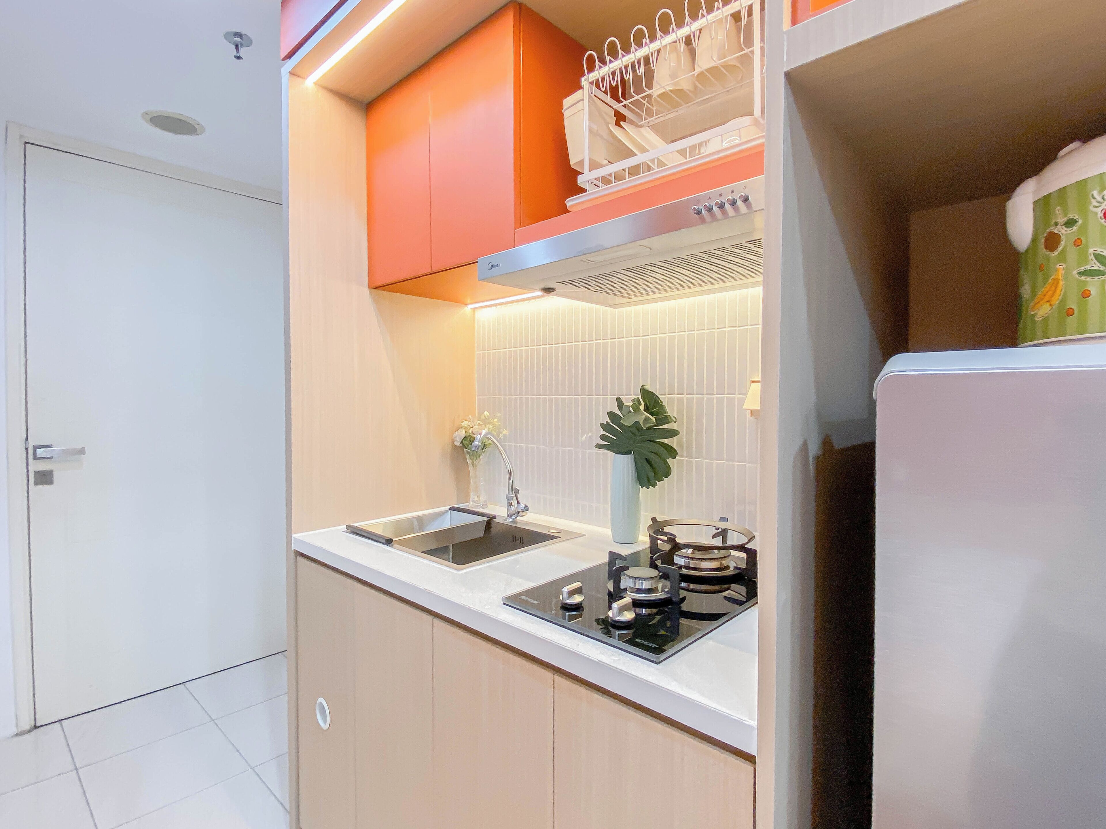 A compact kitchen with a double sink, a gas stove, and a dish rack above the counter.