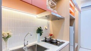 A modern kitchen with a stainless steel sink, a built-in stove, and a compact refrigerator. - Strategic Studio At Apartment Springlake Summarecon Bekasi (Bekasi)
