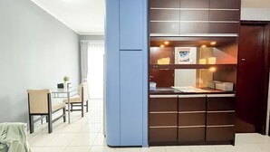 A modern kitchen with a built-in oven, a dining area with a table and chairs, and a blue accent wall. - Cozy And Modern 2Br Apartment Marina Ancol (Jakarta)