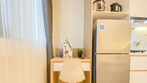 Una kitchenette con un refrigerador, una tetera y una cafetera sobre la encimera.