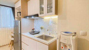 Una cocina moderna con un refrigerador de acero inoxidable, horno empotrado, microondas, lavamanos y dispensador de agua.