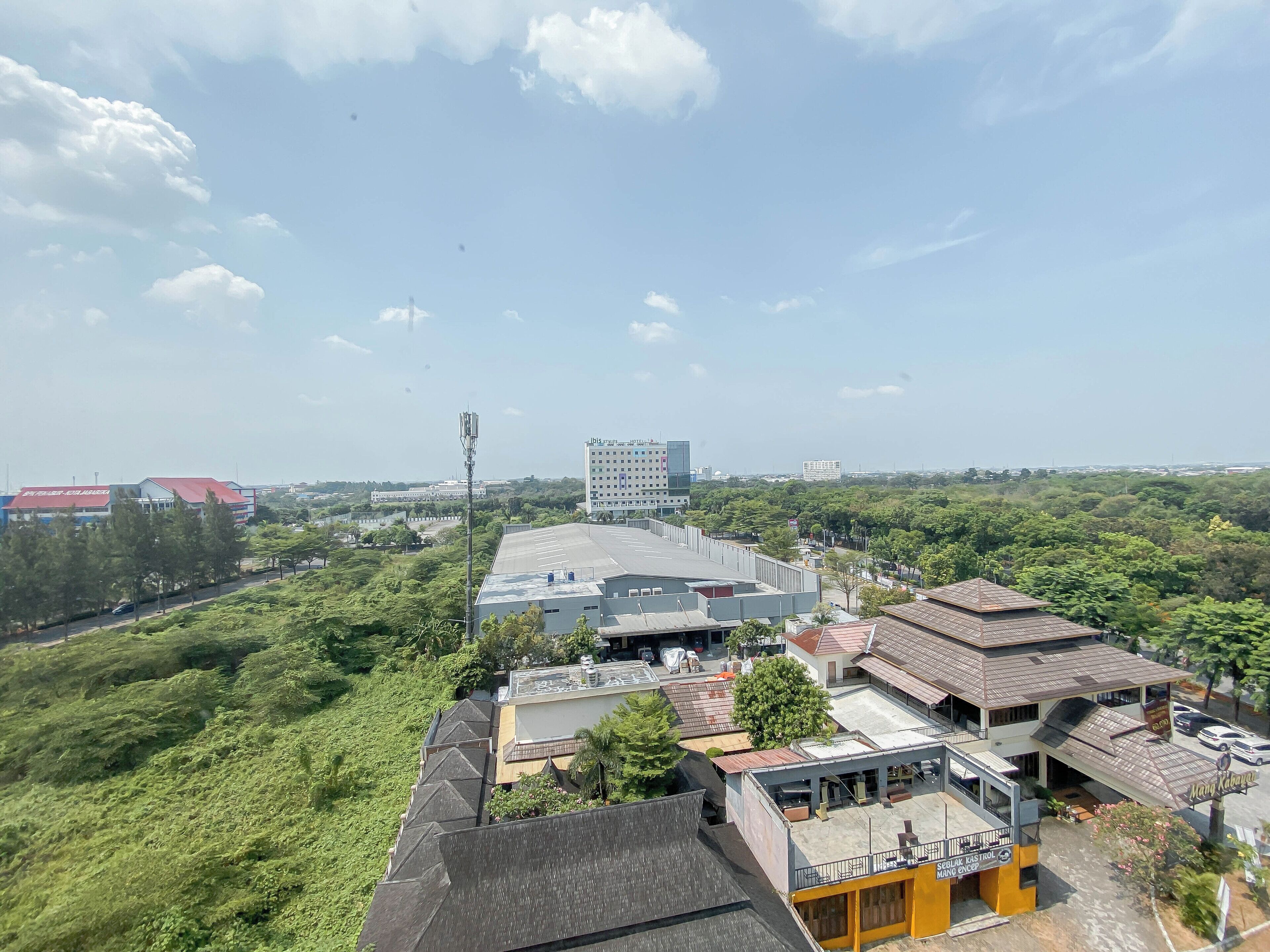 A hotel with multiple buildings, a parking area, and surrounding greenery.