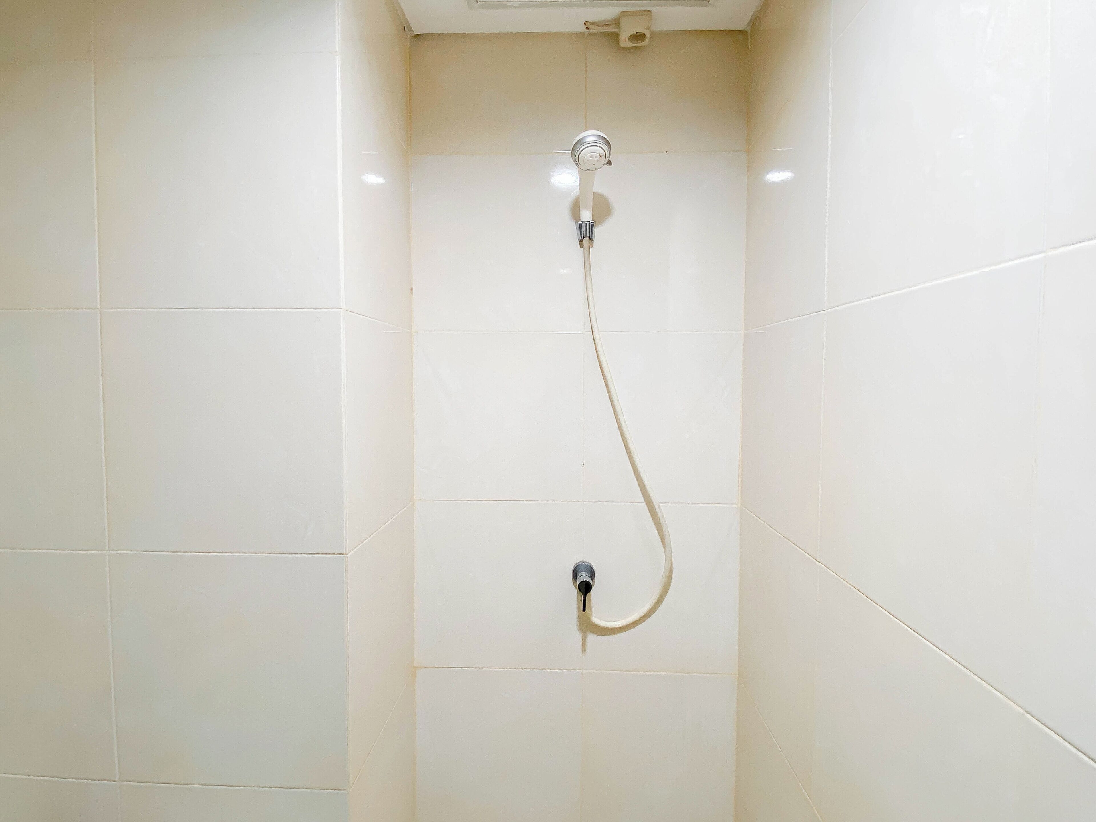 A shower with a handheld showerhead and a wall-mounted control valve.