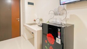 Eine kleine Küche mit Spüle, Geschirrgestell und einem Kühlschrank mit Rosenmotiv.