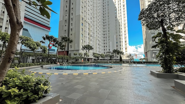 A residential area with a swimming pool, tall apartment buildings, and greenery. - Basic 2Br Apartment At Green Bay Pluit (Jakarta)