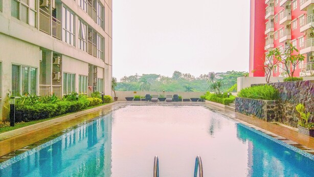 Une piscine avec vue sur deux immeubles, l’un doté de balcons et l’autre d’une façade rouge.