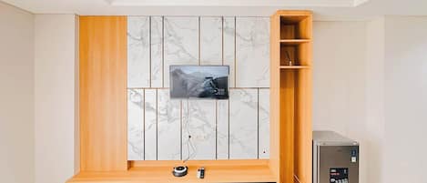 Un meuble de divertissement moderne doté d’un téléviseur à écran plat, d’étagères en bois et d’un système de haut-parleurs intégré.