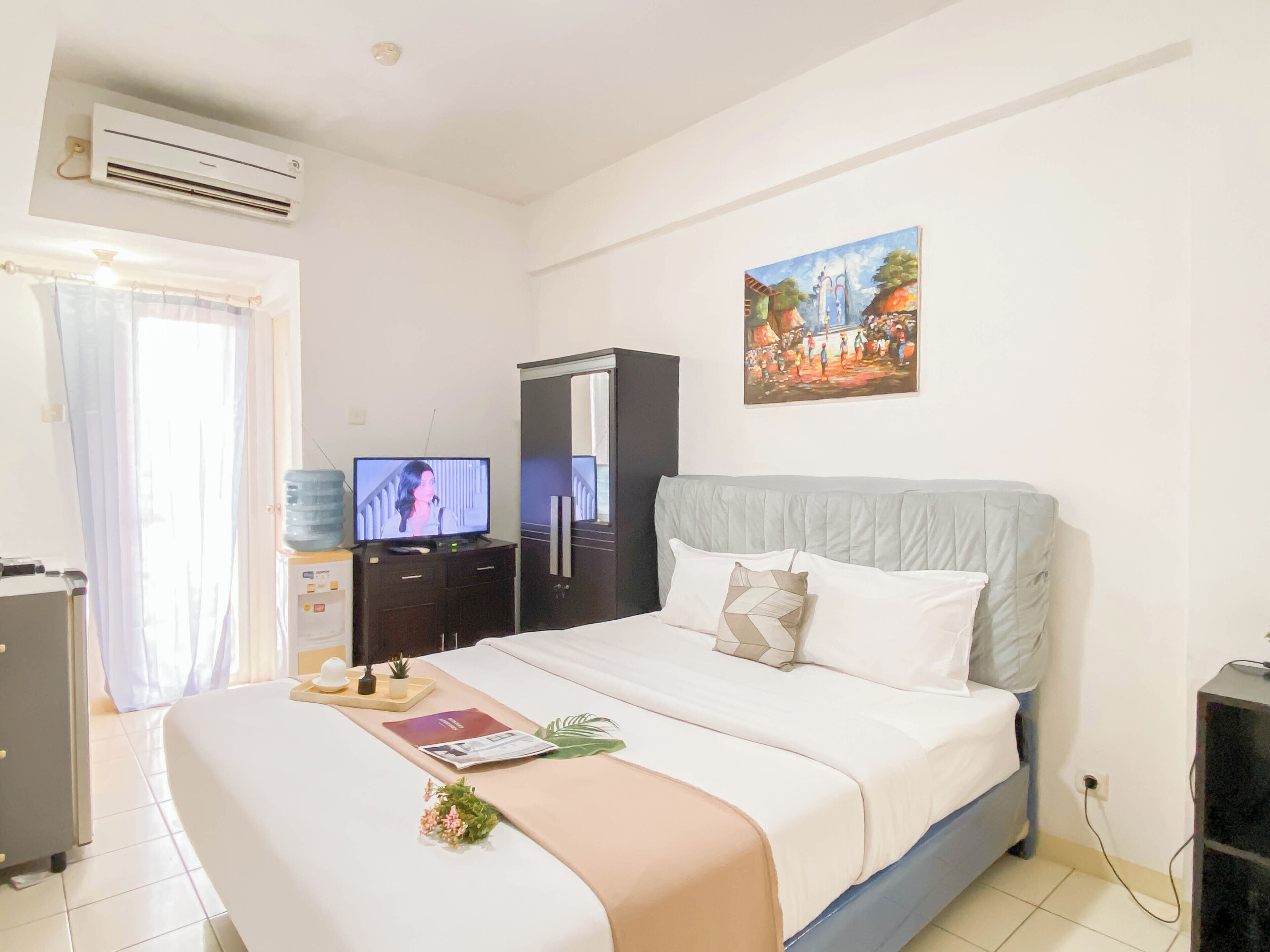Ein Hotelzimmer mit einem Bett, einem Fernseher, einem Kleiderschrank und einem Bild an der Wand.