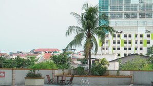 A swimming pool with lounge chairs and a palm tree, surrounded by a concrete wall and greenery. - Basic Studio Near Station At Margonda Residence 2 Apartment (Depok)